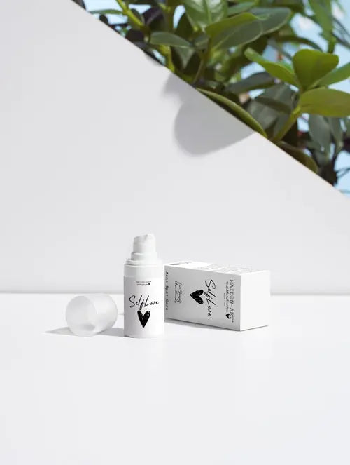 acne spot care serum displayed next to its box on a clean surface with greenery in the background.